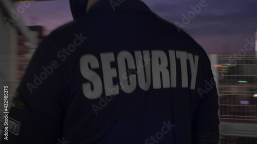 Rear view of a security guard in uniform patrolling in a commercial area.
