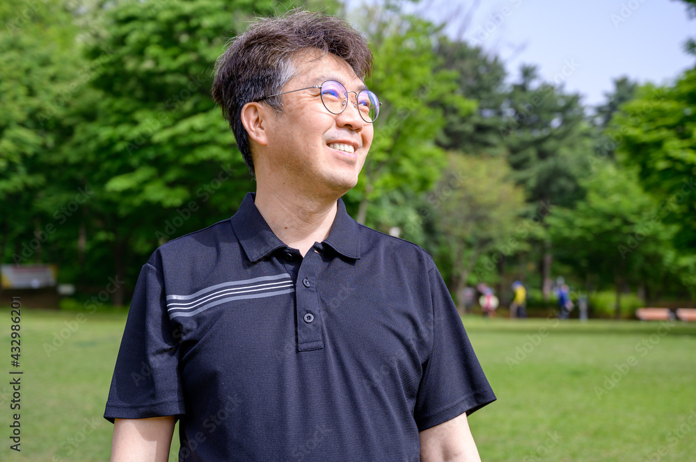 Portrait of a middle-aged Asian man smiling on the lawn wearing a T-shirt. Portrait of a middle-aged Asian man smiling on the lawn wearing a T-shirt.