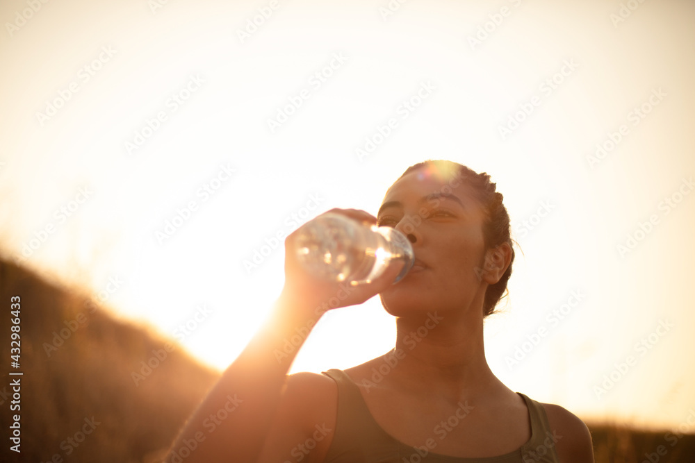 Sporty young woman drinking water outdoors. Time for refresh. - obrazy, fototapety, plakaty 