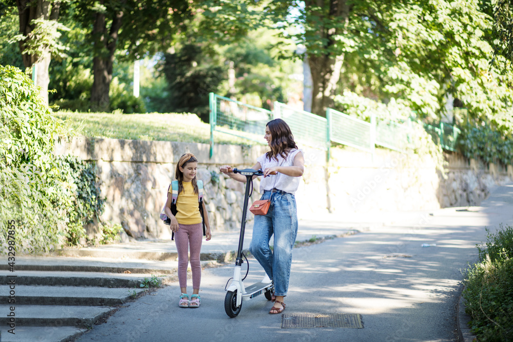 This is so fun thing. Mother and daughter together in the park. Woman riding scooter. This is so fun thing. Mother and daughter together in the park. Woman riding scooter.