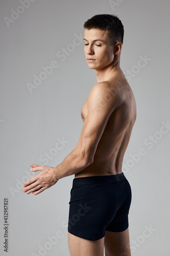 guy with a pumped up torso in black panties on a gray background back view bodybuilder fitness