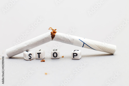 broken cigarette with the word stop on gray background close. stop smoking concept