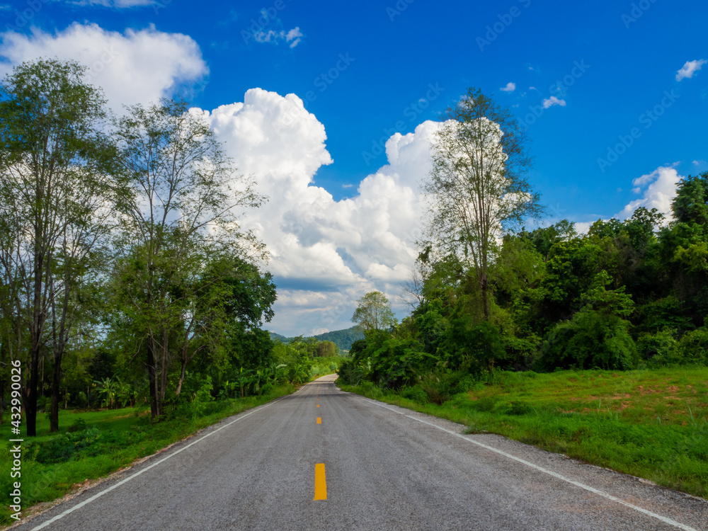 wide asphalt highway with road markings against a blue sky with clouds. Summer sunny day. wide asphalt highway with road markings against a blue sky with clouds. Summer sunny day.