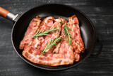 Hot fried bacon with rosemary on a black background.