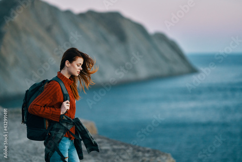 traveler in nature in the mountains in a sweater with a backpack on the back