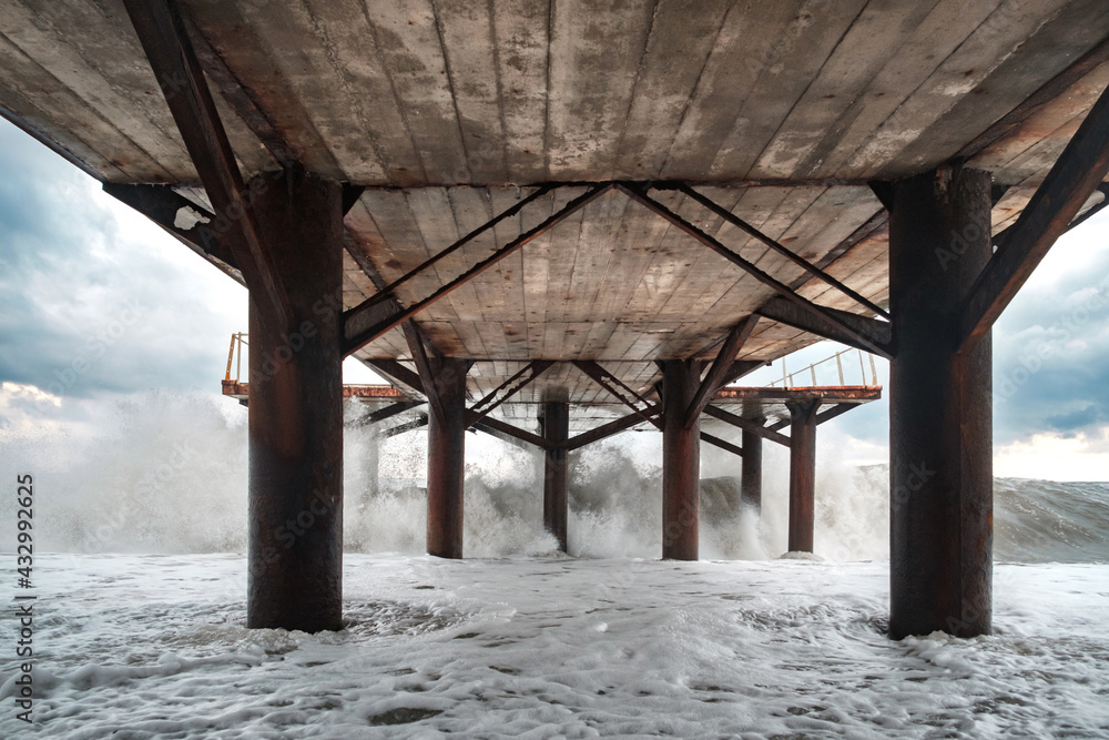 Large waves breaking on the poles of the pier, view from under the pier Large waves breaking on the poles of the pier, view from under the pier