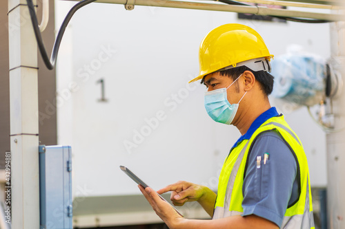 Engineer with safety helmet at the construction site typing on a digital tablet