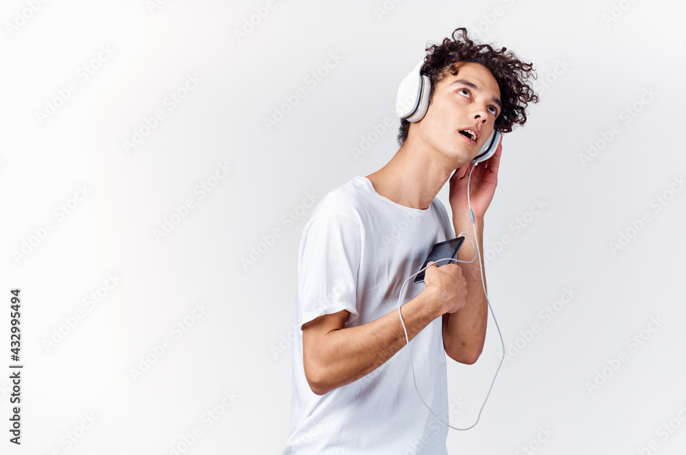 man with curly hair in white t-shirt listening to music with headphones phone technology man with curly hair in white t-shirt listening to music with headphones phone technology