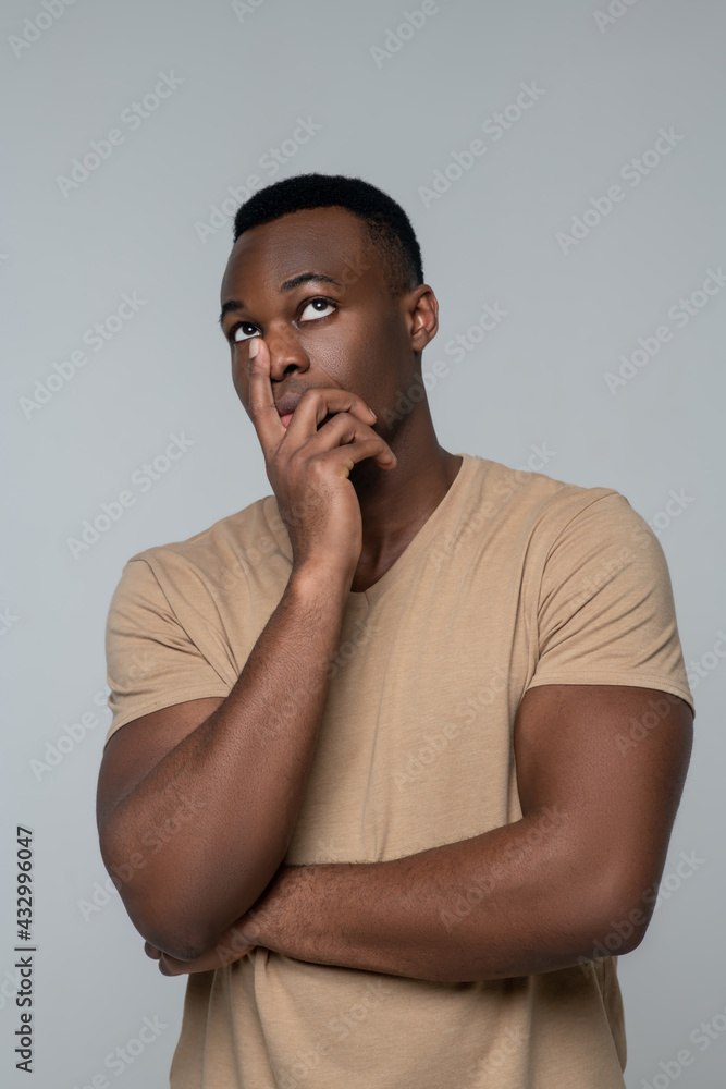 Young pensive african american man standing in studio photo Young pensive african american man standing in studio photo