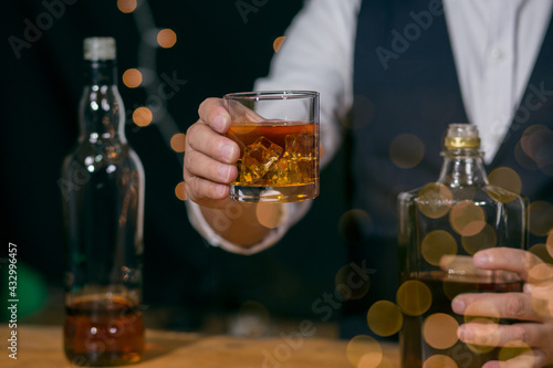 Barman pouring whiskey glass on beautiful bokeh background