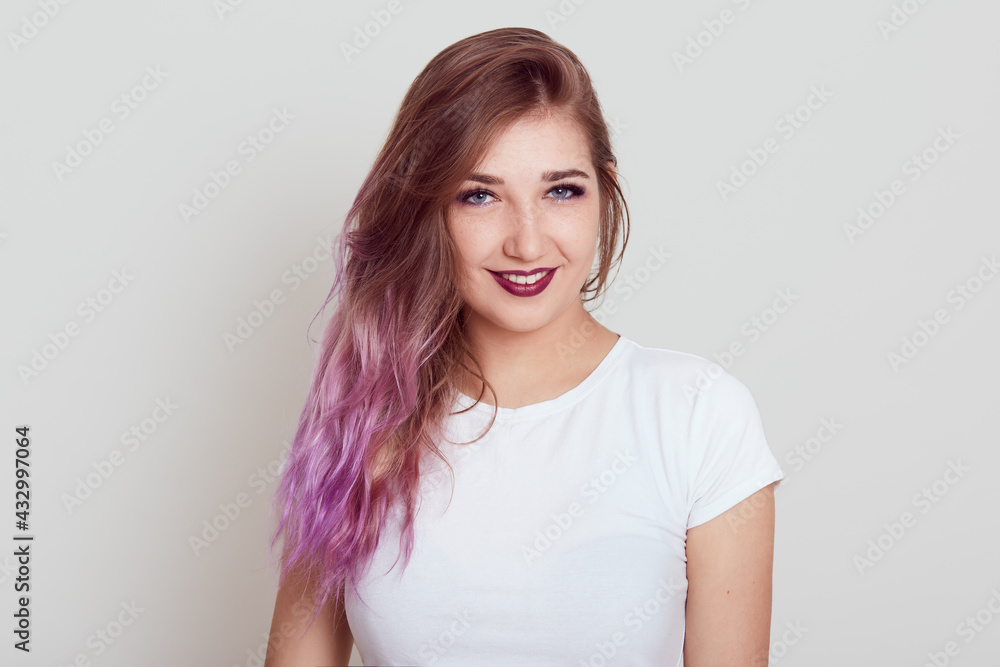 Young beautiful self confident lady in white casual t shirt looking at camera and expressing positive emotions, sees something pleasant, posing isolated over gray background. Young beautiful self confident lady in white casual t shirt looking at camera and expressing positive emotions, sees something pleasant, posing isolated over gray background.