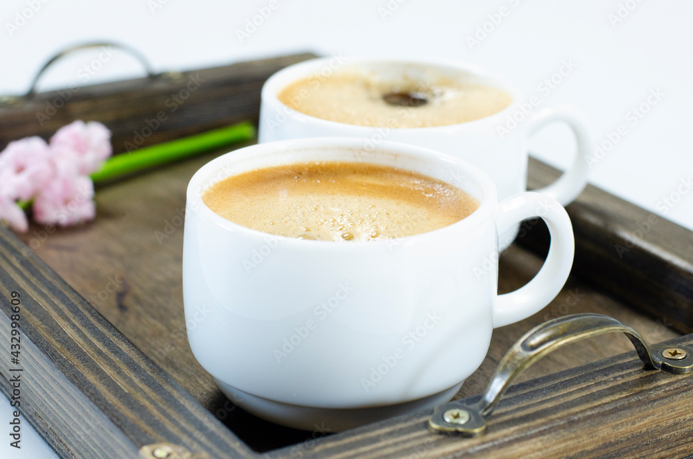 Obraz premium Two cups of frothy coffee. On a wooden tray. Hyacinth flowers. On white background.