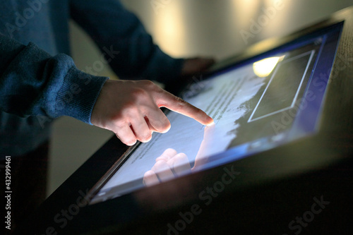 A boy uses the interactive touchscreen of an electronic multimedia kiosk at a museum of modern history. Education, training and technology concept photo