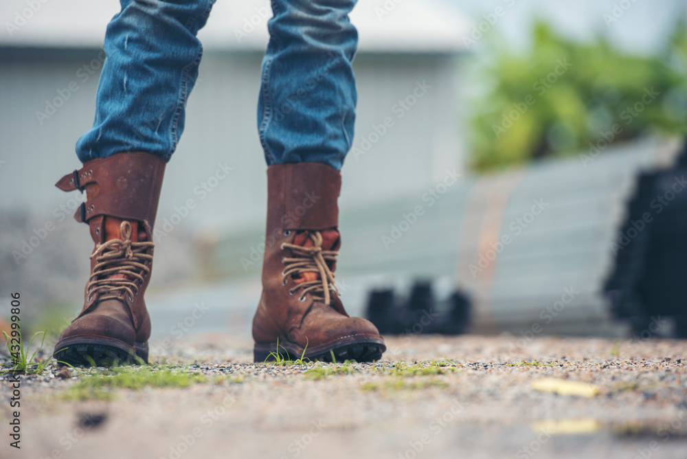 Men wear construction Boots safety footwear for worker at construction site. Engineer Wear Jeans Brown Boots Worker on Background of Refinery. Engineer safety industry fashion footwear walking outdoor Men wear construction Boots safety footwear for worker at construction site. Engineer Wear Jeans Brown Boots Worker on Background of Refinery. Engineer safety industry fashion footwear walking outdoor