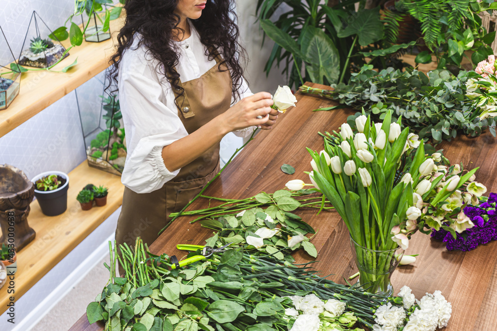 Obraz premium Attractive young woman florist is working in a flower shop.