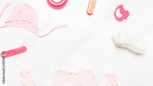 Childcare concept. children's accessories. items for newborns. Hygiene and health of babies. baby clothes for little girl, milk bottle, comb, toys. Frame. On white background. top view. Space for text