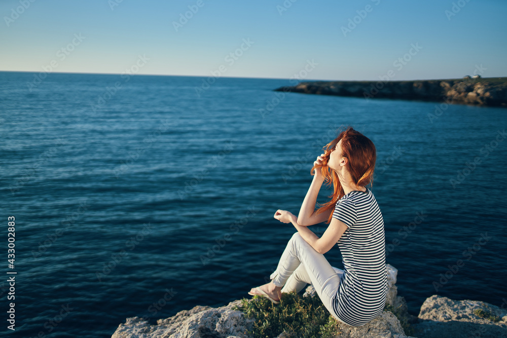 romantic woman on a rock near the sea in the mountains sunset summer back view romantic woman on a rock near the sea in the mountains sunset summer back view