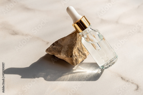 A glass bottle with aromatic oil or serum on a stone. Natural Organic Spa Cosmetic concept. Front view.
