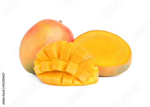 Delicious whole and cut mangoes on white background