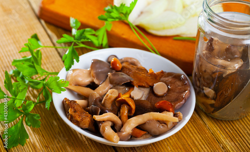 Various pickled mushrooms in plate with onions and parsley