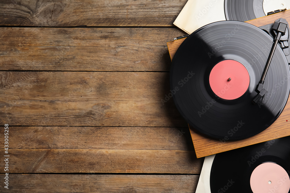 Modern player and vinyl records on wooden background, flat lay. Space for text - obrazy, fototapety, plakaty 