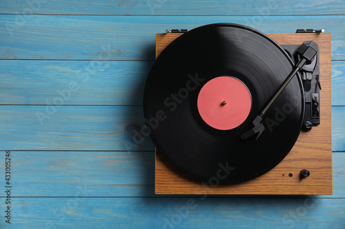 Modern vinyl record player with disc on blue wooden background, top view. Space for text