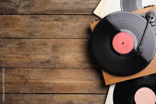 Modern player and vinyl records on wooden background, flat lay. Space for text photo