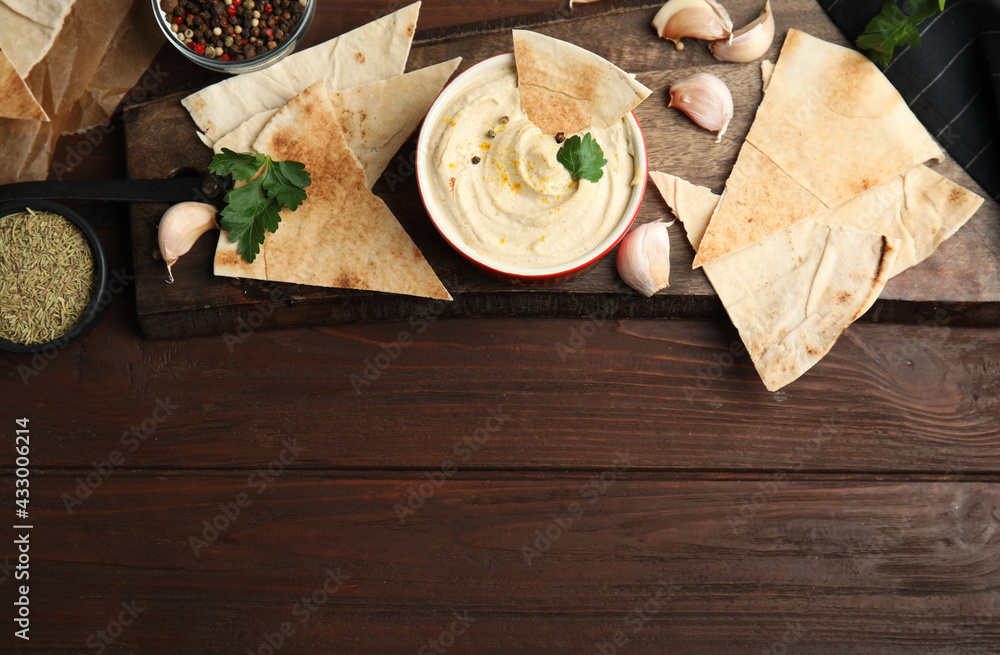 Flat lay composition with delicious hummus and pita chips on wooden table. Space for text Flat lay composition with delicious hummus and pita chips on wooden table. Space for text