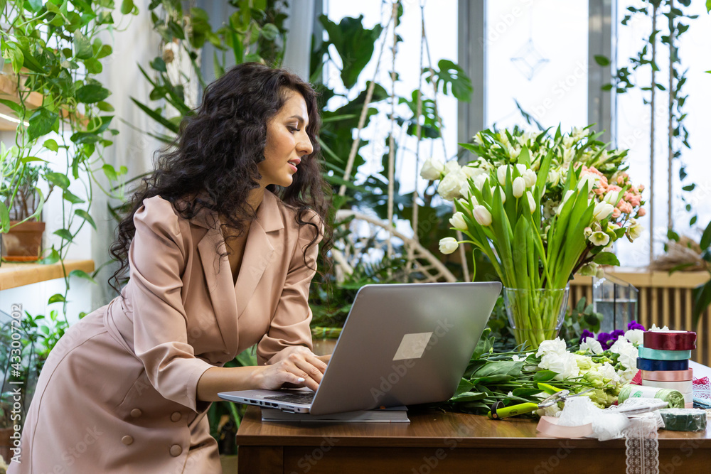 Attractive young woman florist is working in a flower shop. Attractive young woman florist is working in a flower shop.