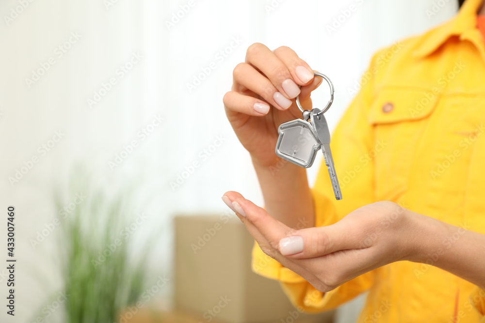 Woman holding key in new house, closeup. Space for text - obrazy, fototapety, plakaty 