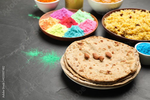 Traditional Indian food and color powders on black table. Holi festival celebration photo