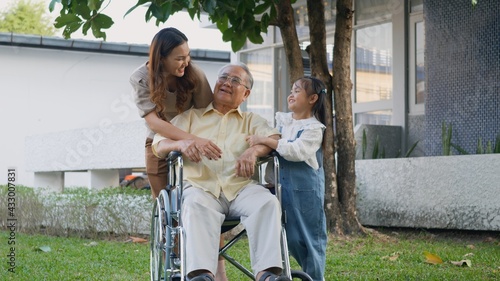 Disabled senior grandpa on wheelchair with grandchild and mother in park, Happy Asian three generation family having fun together outdoors backyard, Grandpa and little child smiling and laughed