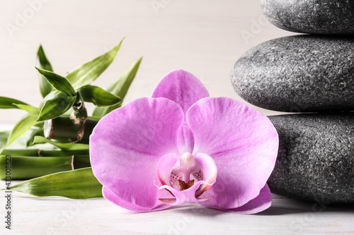Spa stones  bamboo and beautiful orchid flower on white table  closeup