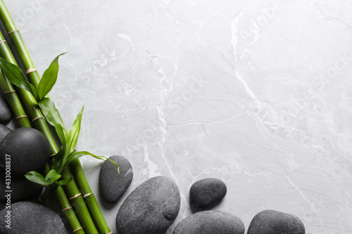 Photography Spa stones and bamboo stems on light grey table, flat lay