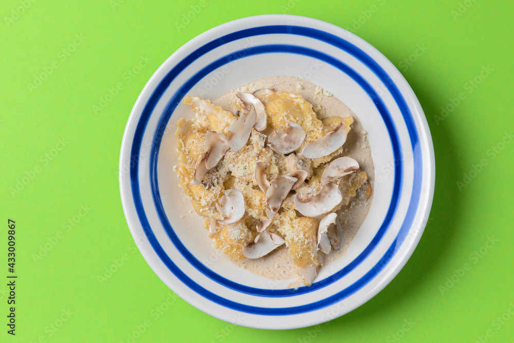 Pasta Penne with Chicken and Mushroom under Parmesan Cheese. Served in a white plate over green background. Pasta Penne with Chicken and Mushroom under Parmesan Cheese. Served in a white plate over green background.
