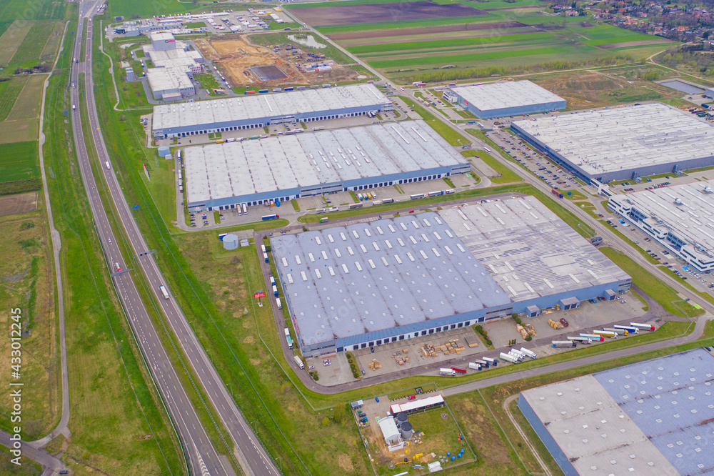 Aerial view of goods warehouse. Logistics center in industrial city zone from above. Aerial view of trucks loading at logistic center. View from drone. Aerial view of goods warehouse. Logistics center in industrial city zone from above. Aerial view of trucks loading at logistic center. View from drone.