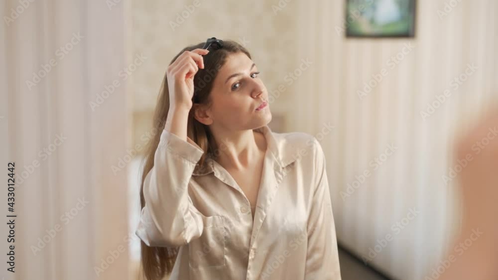 Pretty young woman doing a roller head massage in front of a mirror Pretty young woman doing a roller head massage in front of a mirror