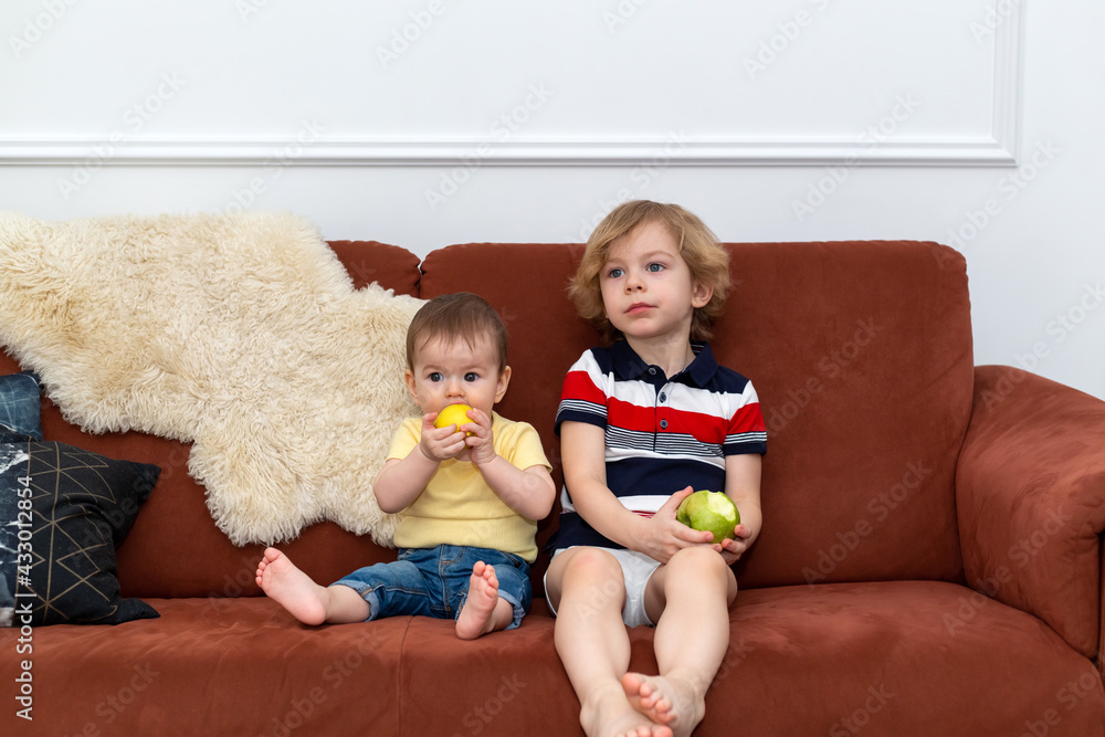 Two brothers eat apples on the couch. Two brothers eat apples on the couch.