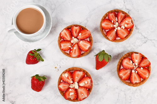 Top view of small tartlet pastries topped with strawberry fruits and white chocolate sprinkles photo