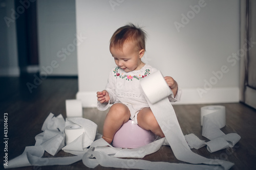 Funny kid Toddler sits on a pot with toilet paper, concept of teaching pot, child autonomy. Baby Child Pissing And Splits Many Rolls of Toilet Paper, Toddler scatters toilet paper photo