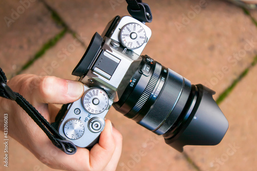 Closeup of a mirrorless camera body with lens held by a person hand
