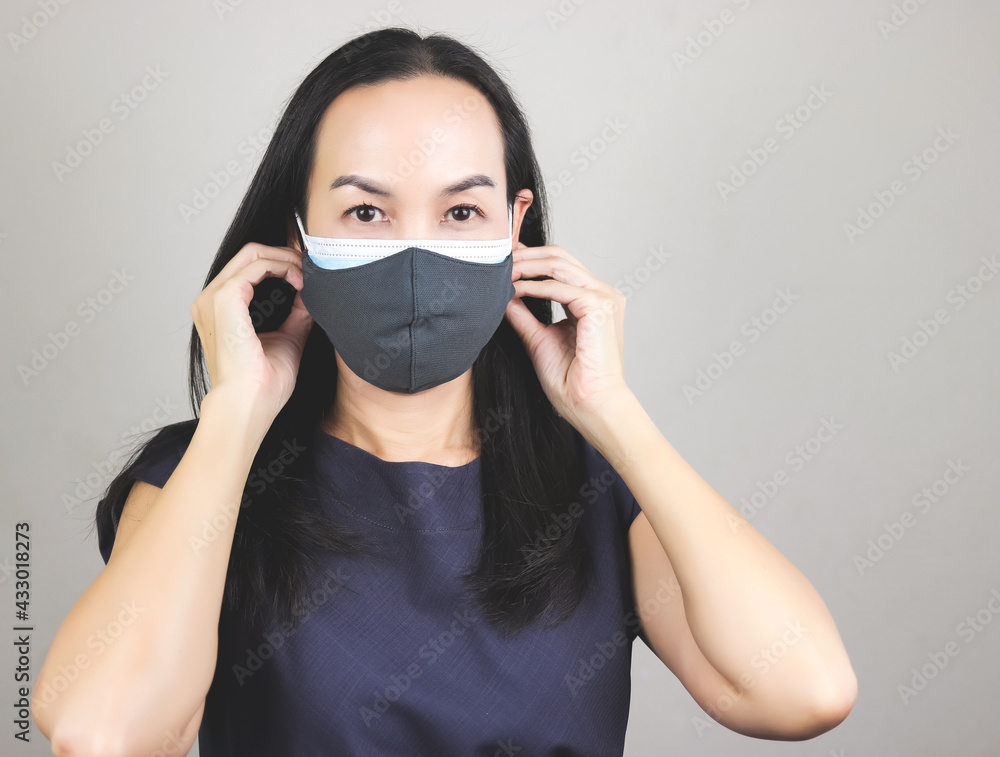 Asian woman wearing double face masks or two face masks for better protection from coronavirus or covid-19 outbreak - concept of safety, healthcare, medical and hygiene. Asian woman wearing double face masks or two face masks for better protection from coronavirus or covid-19 outbreak - concept of safety, healthcare, medical and hygiene.