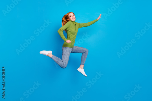 Full length body size view of attractive glad cheerful girl jumping running isolated over bright blue color background