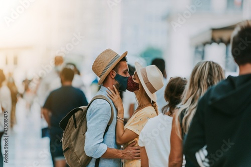 Couple wearing protective face masks kissing on city street - New normal concept with boyfriend and girlfriend in love outdoor - People, healthcare and love concept photo