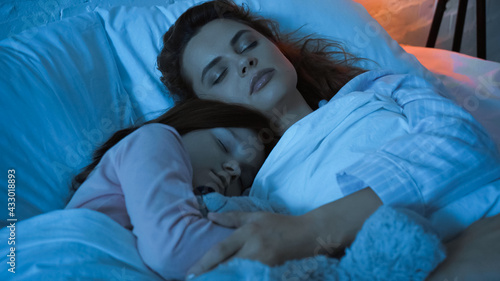 Woman hugging child while sleeping during night