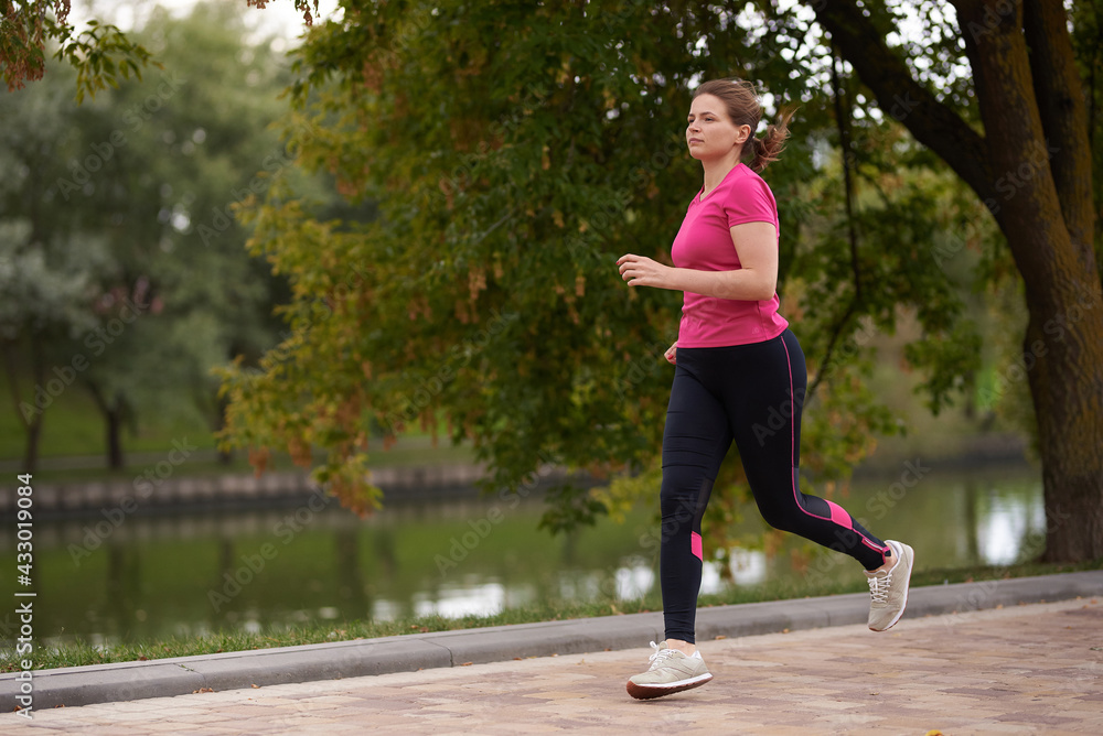 young woman in sportswear runs along in the park path young woman in sportswear runs along in the park path