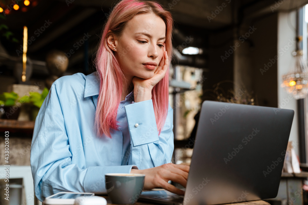 Young white woman with pink hair working with laptop in cafe Young white woman with pink hair working with laptop in cafe