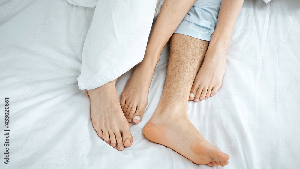 top view of barefoot couple lying on bed