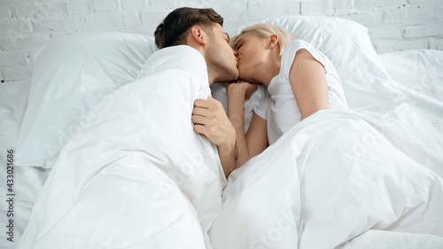 young woman and man kissing in bed