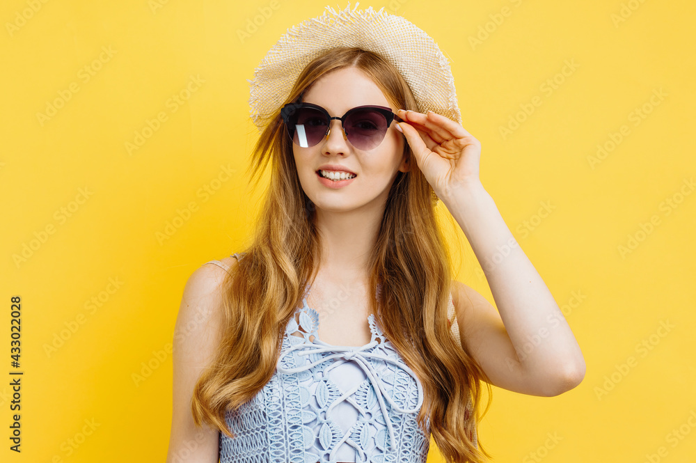 young summer woman with hat and sunglasses, over isolated yellow studio background young summer woman with hat and sunglasses, over isolated yellow studio background